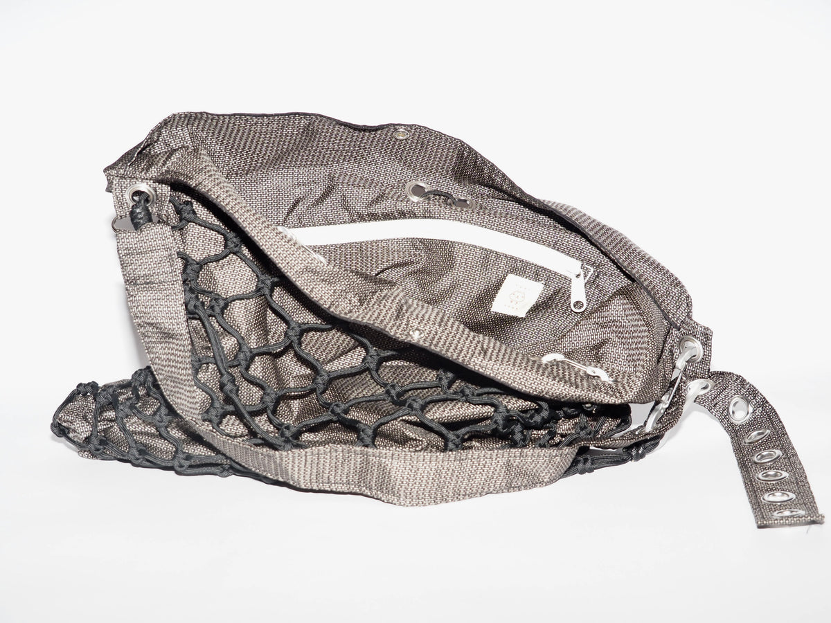 Handmade bag made of upcycled silk kimono and encased in a hand-knotted paracord. The fabric features black and white all-over print. The strap includes grommets and a carabiner for adjustability.