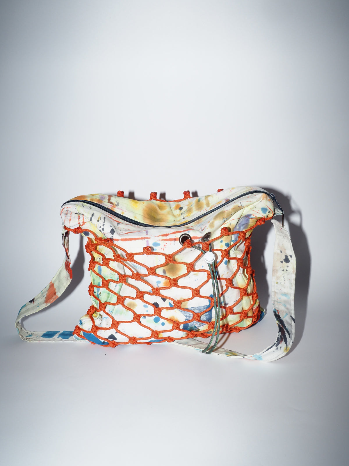 Handmade bag encased in hand-knotted paracord. Fabric is made by bay-area artis dymline. It features abstracts splatters and marks that are a natural by-product of their printing process.